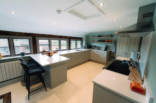Notehouse Farms kitchen with pale green cabinetry, white countertops, breakfast bar seating, and large windows overlooking the courtyard